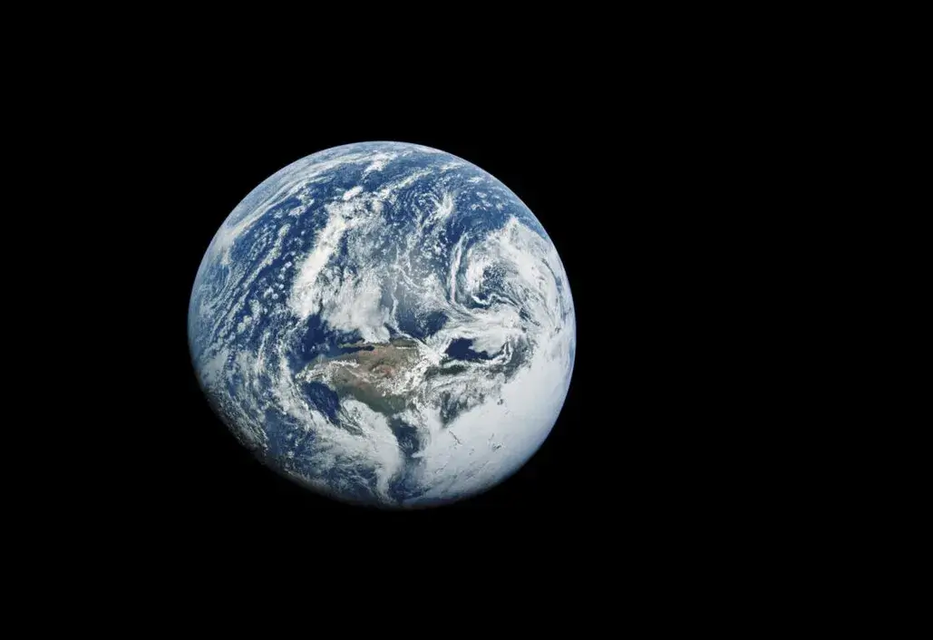 Earth floating in the darkness of space, showing swirling white clouds over blue oceans and brown continents, with no visible text, conveying a sense of isolation and tranquility